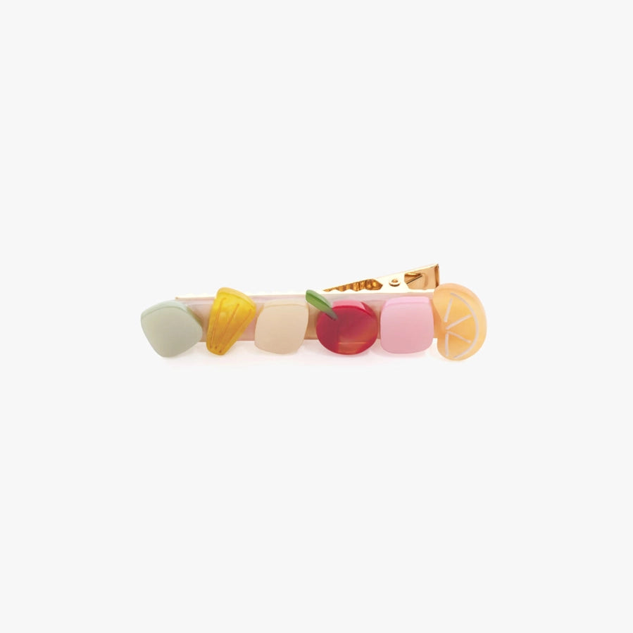 A pastel-colored hair claw clip designed to look like a slice of fruit, featuring a gold metal clasp on a plain white background.