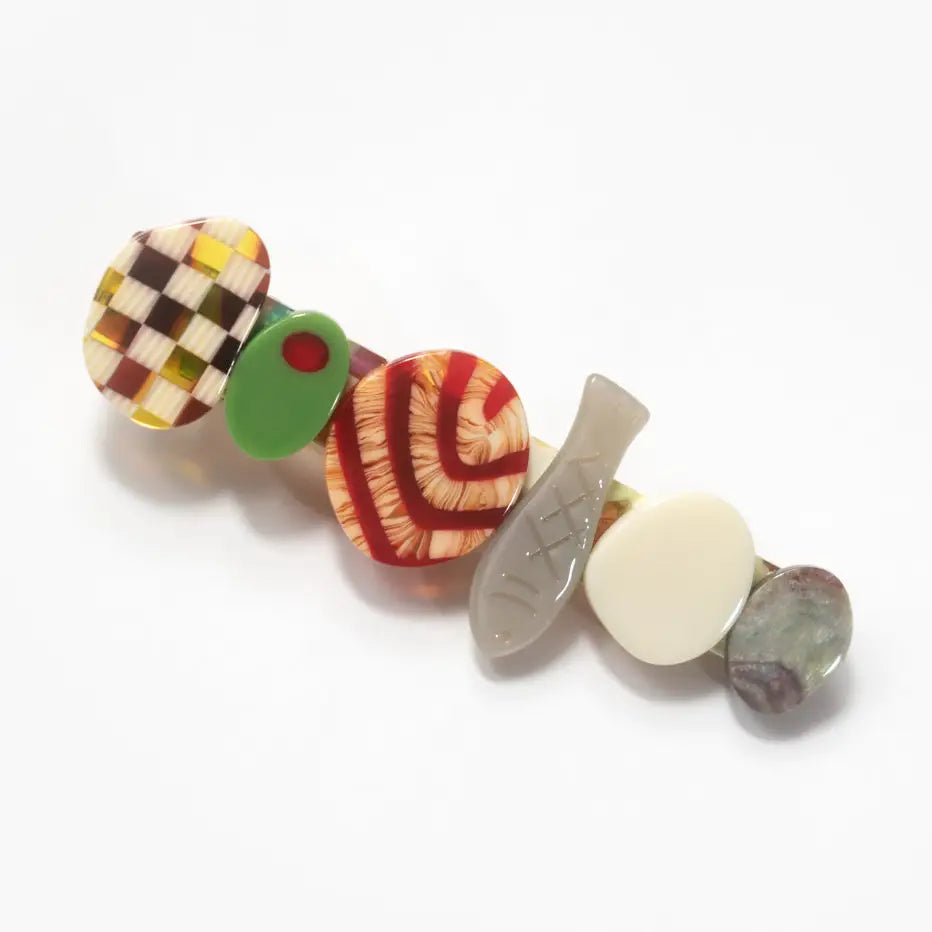 A hair slide with food themed design sits on a white background