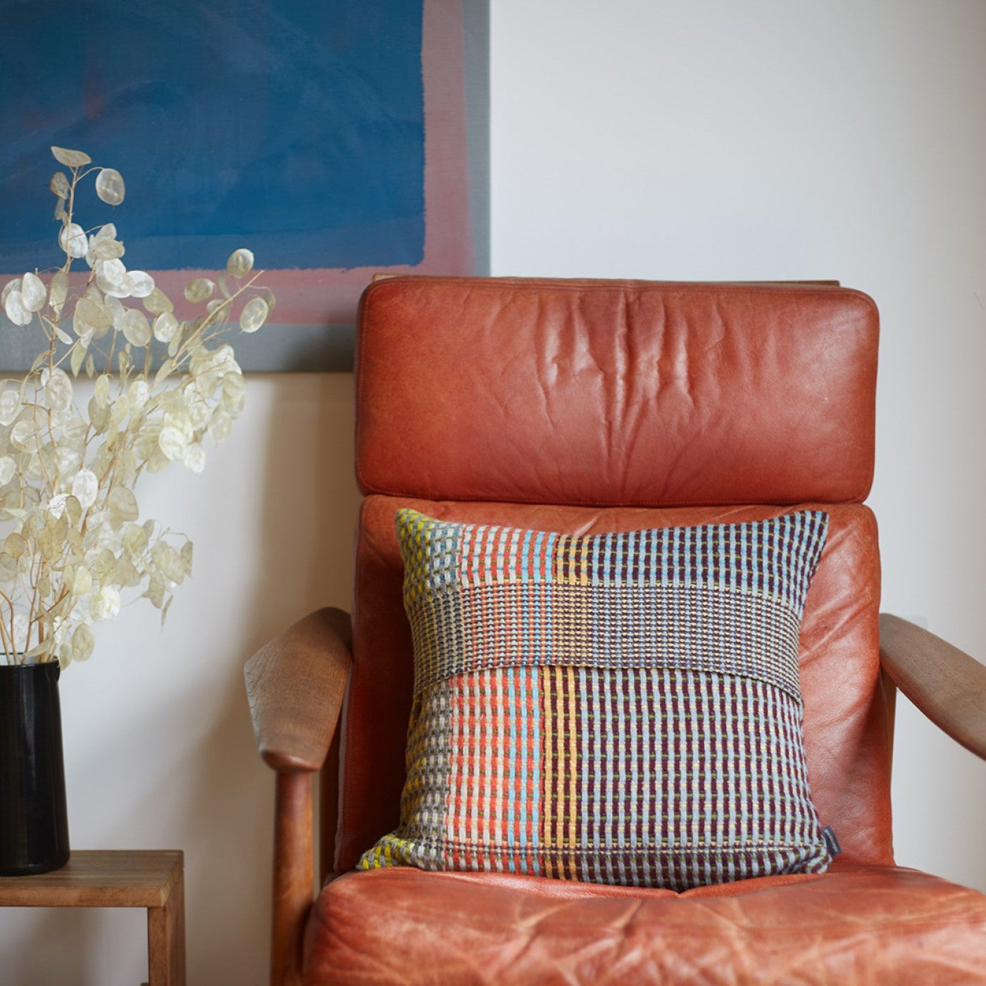 Multicolored woven cushion on a leather armchair.