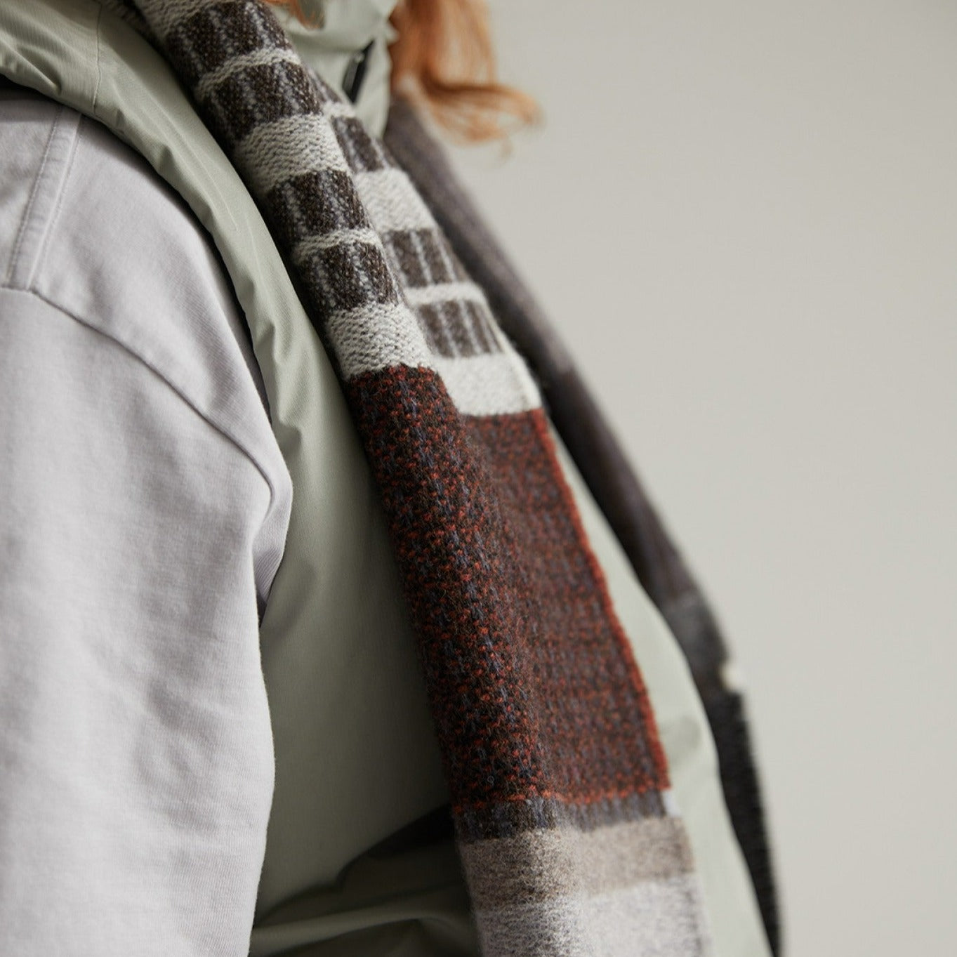 A textured wool scarf in brown, gray, and white, with a striped and block pattern.