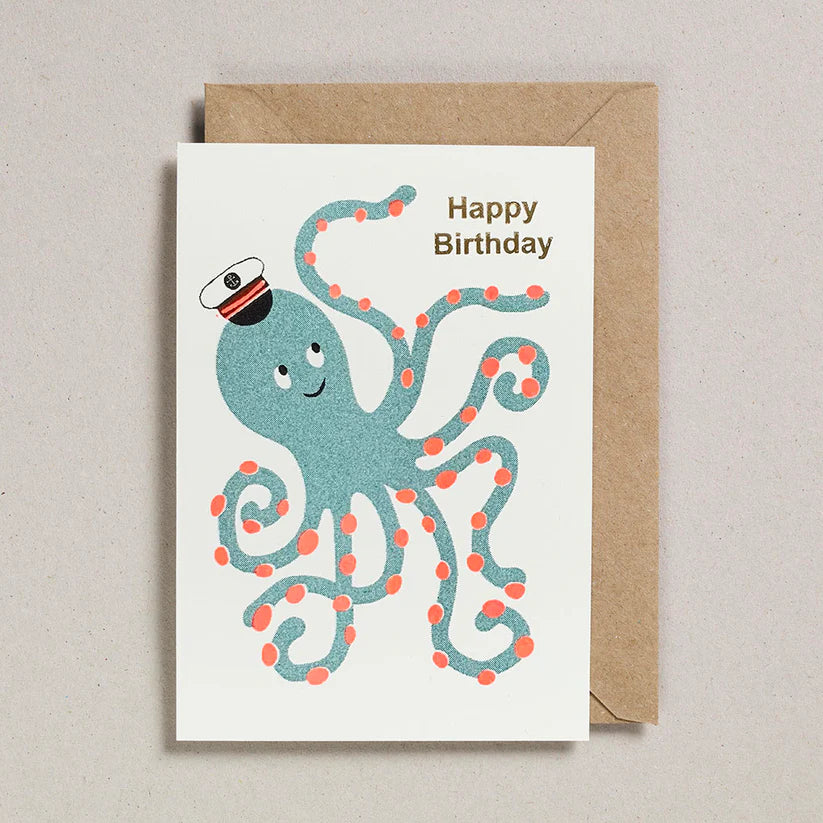 Birthday card with a blue octopus wearing a captain's hat and a brown envelope on a beige background