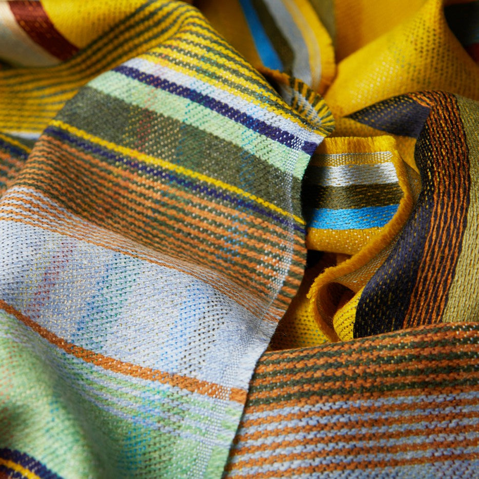 Multicolored striped scarf in shades of yellow, orange, green, and blue.  The fabric has a textured weave.