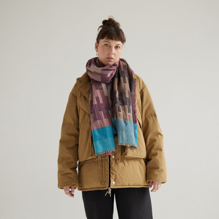 Mustard-colored quilted jacket with a geometric patterned scarf in purple, brown, and teal.