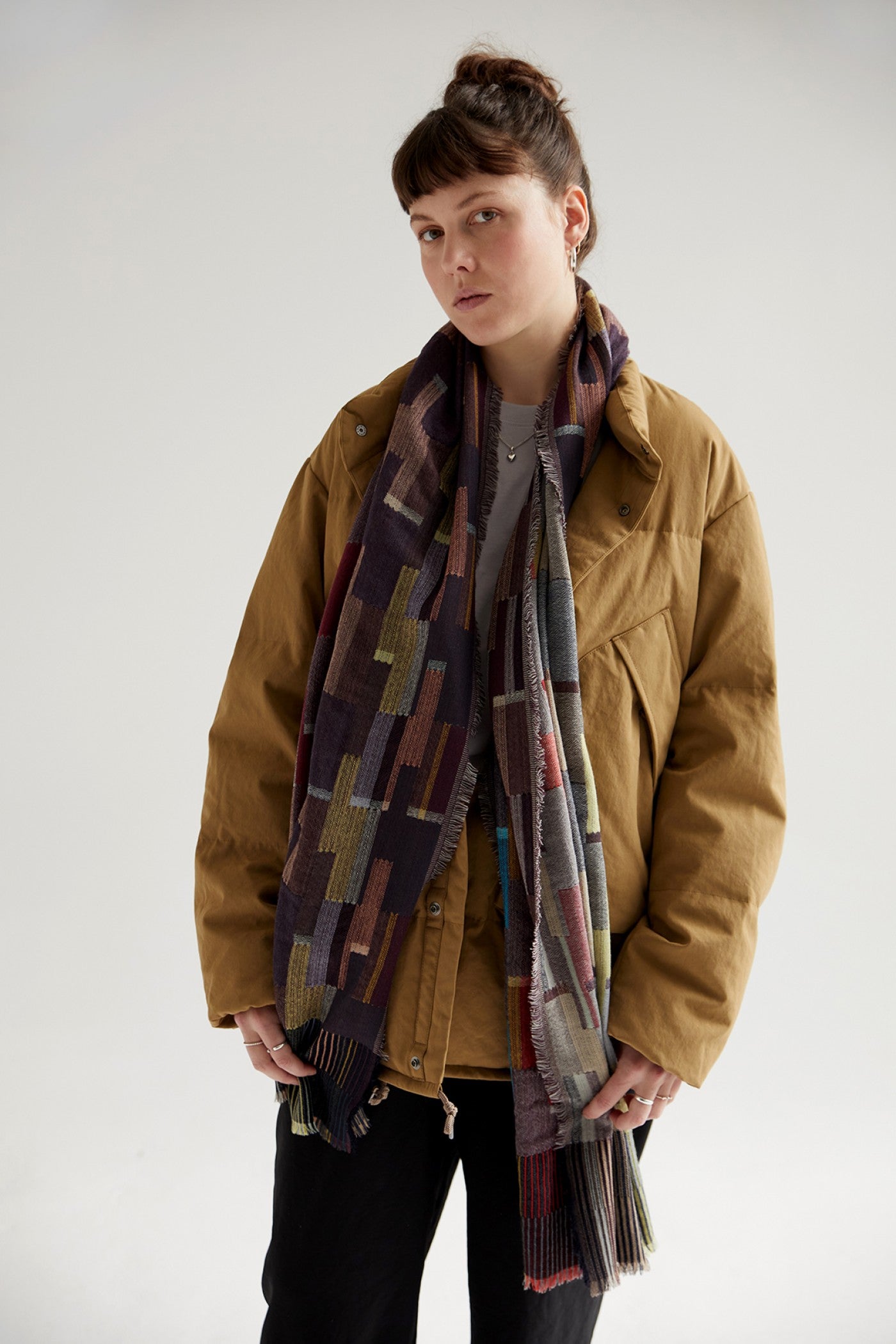 Mustard-colored puffer jacket with a multicolored geometric patterned scarf.