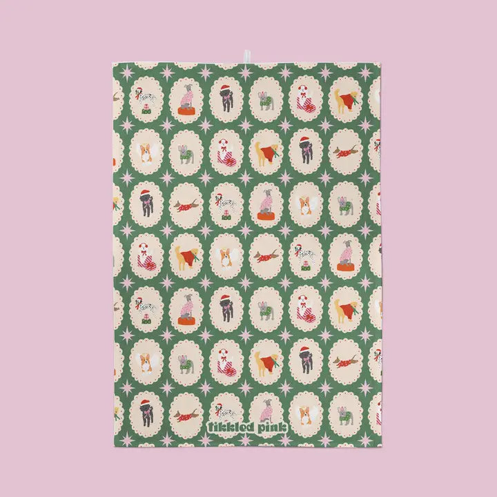 Christmas tea towel featuring a repeating pattern of dogs in festive attire within scalloped circles on a green background.