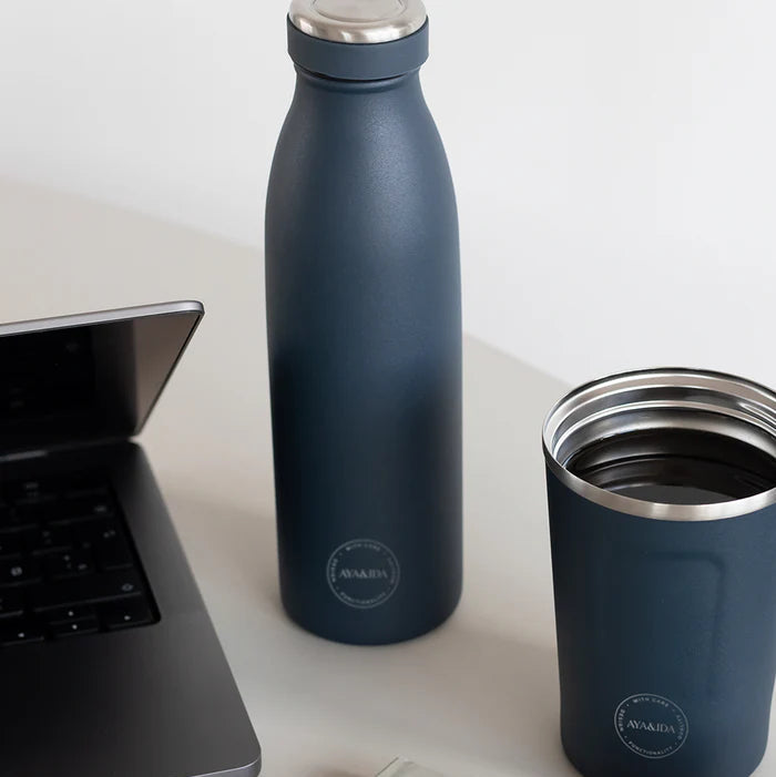 Dark blue insulated bottle and cup on a white surface with a laptop.