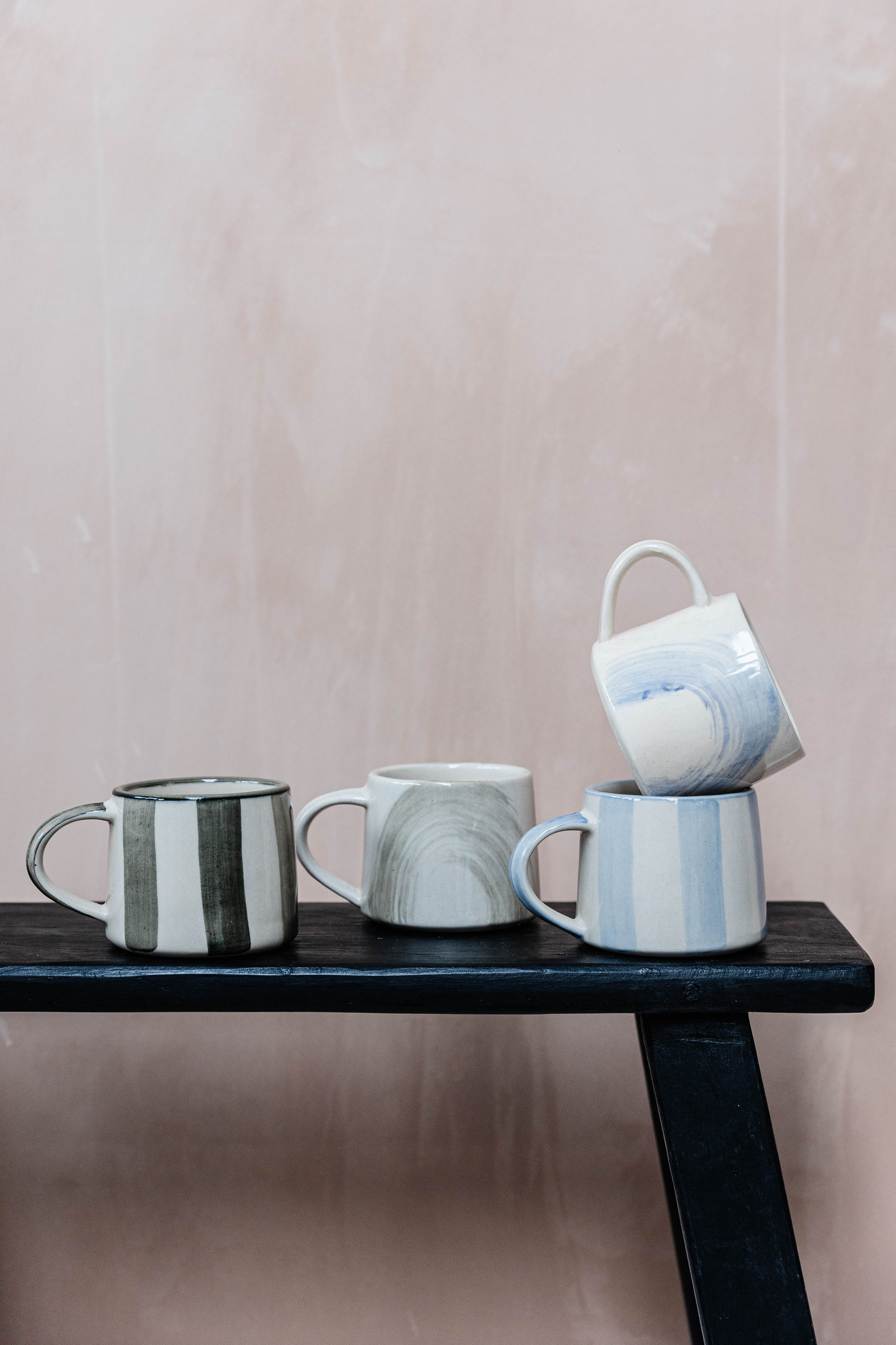 Four hand-painted ceramic mugs in varying designs.