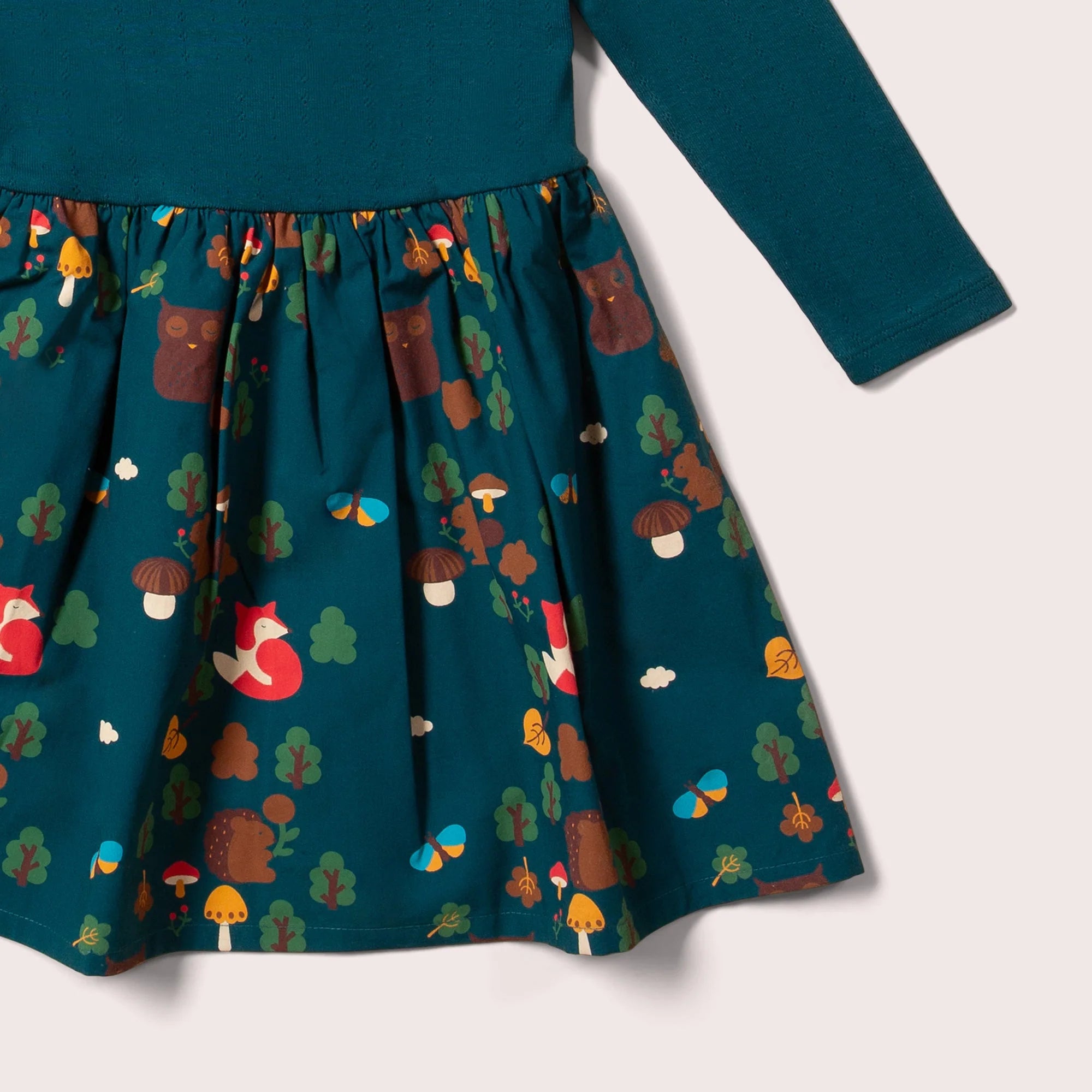 Teal long-sleeved dress with a forest-themed print featuring owls, foxes, squirrels, mushrooms, and butterflies.