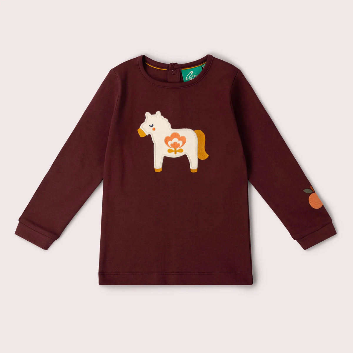A kids' long-sleeve crewneck sweatshirt in deep burgundy, featuring a white wooden toy horse with a flower applique on the chest and an orange graphic on the sleeve, shown against a light beige background.