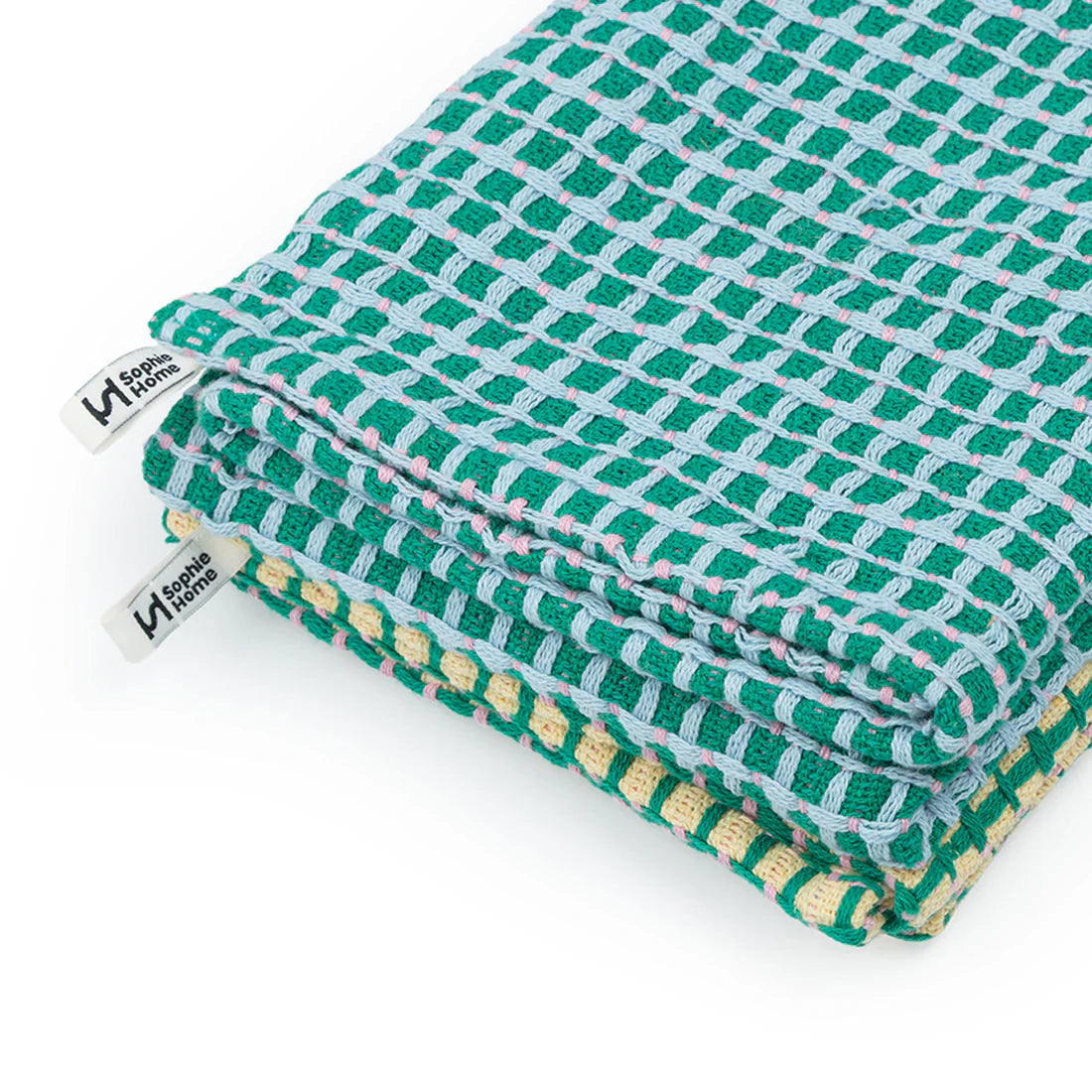 Folded green and yellow checkered fabric with a brand tag on a white background