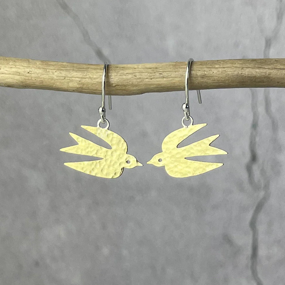 A pair of gold bird-shaped earrings on a gray background
