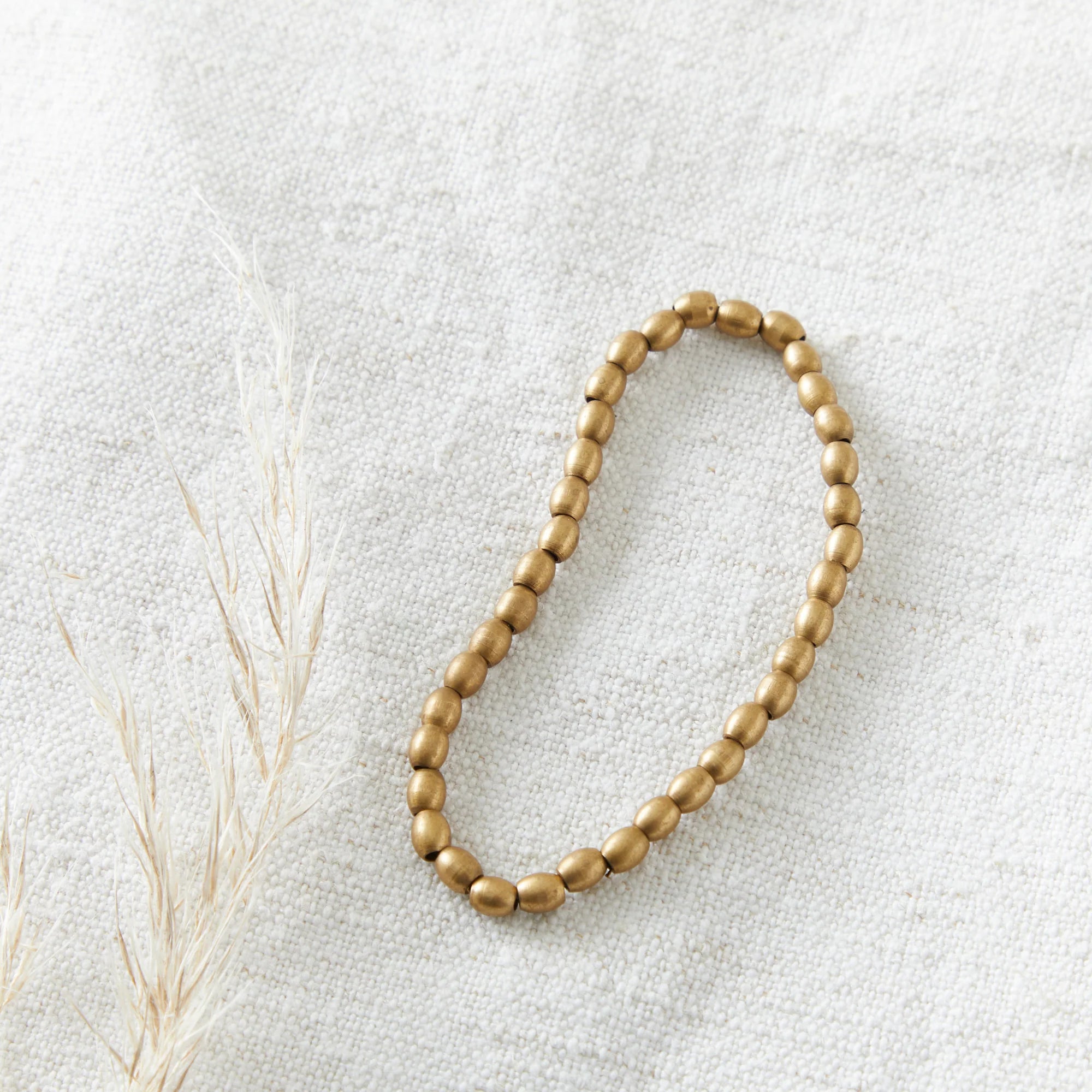 Gold beaded necklace on a light gray background