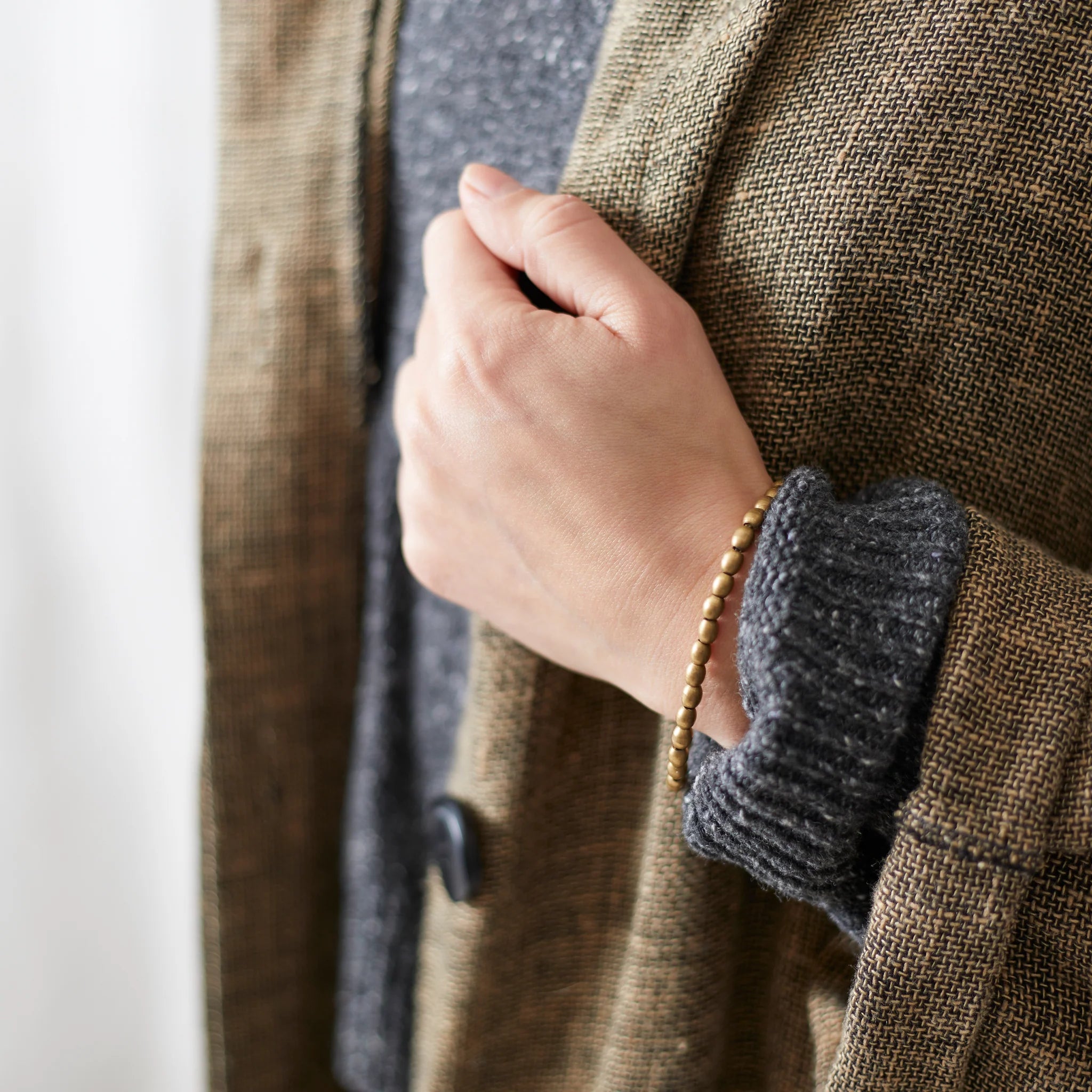 Close-up of a person wearing a brown coat with a textured sleeve and a white background