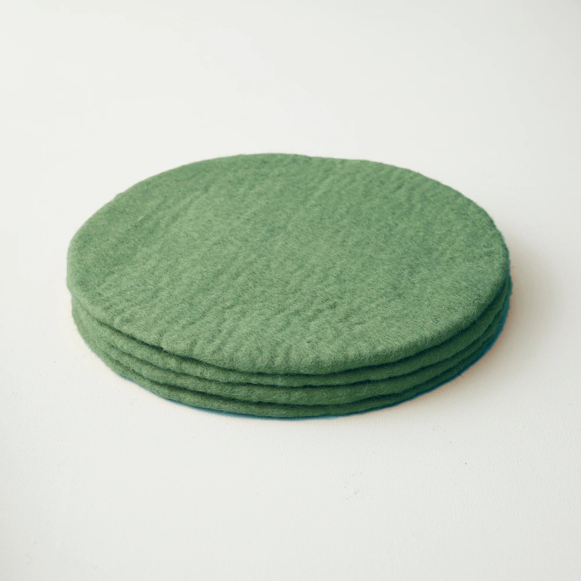 Stack of four round, olive-green felt coasters.