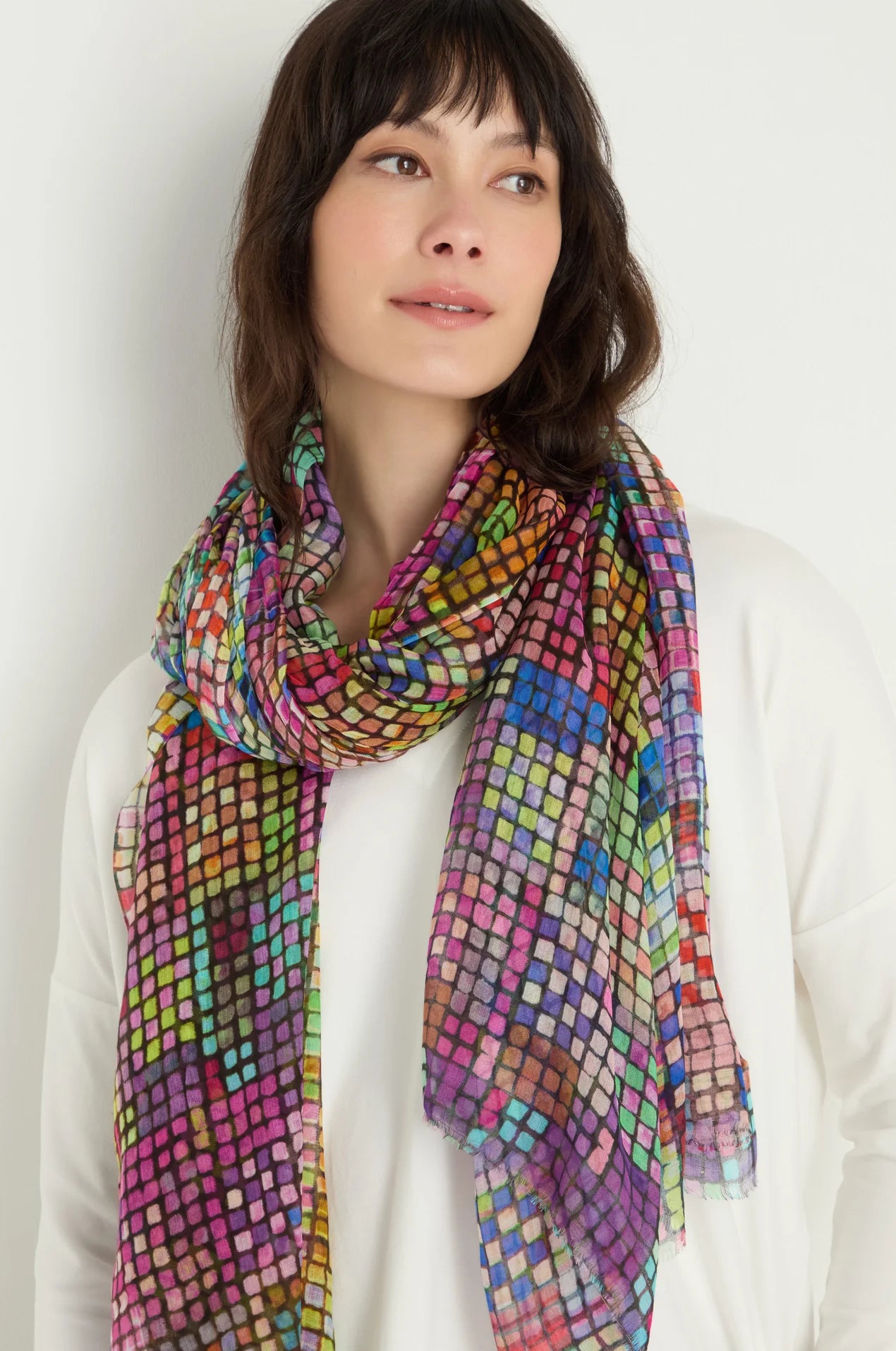 Woman wearing a colorful patterned scarf against a plain background