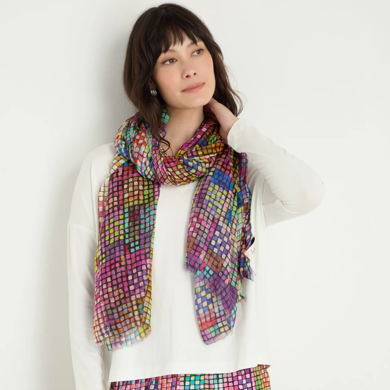 Woman wearing a colorful patterned scarf and pants on a white background
