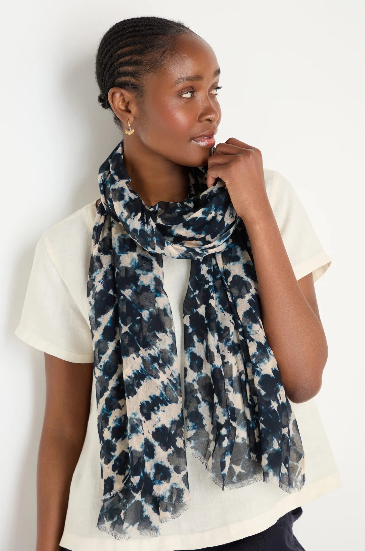 Woman wearing a blue and white patterned scarf on a plain background