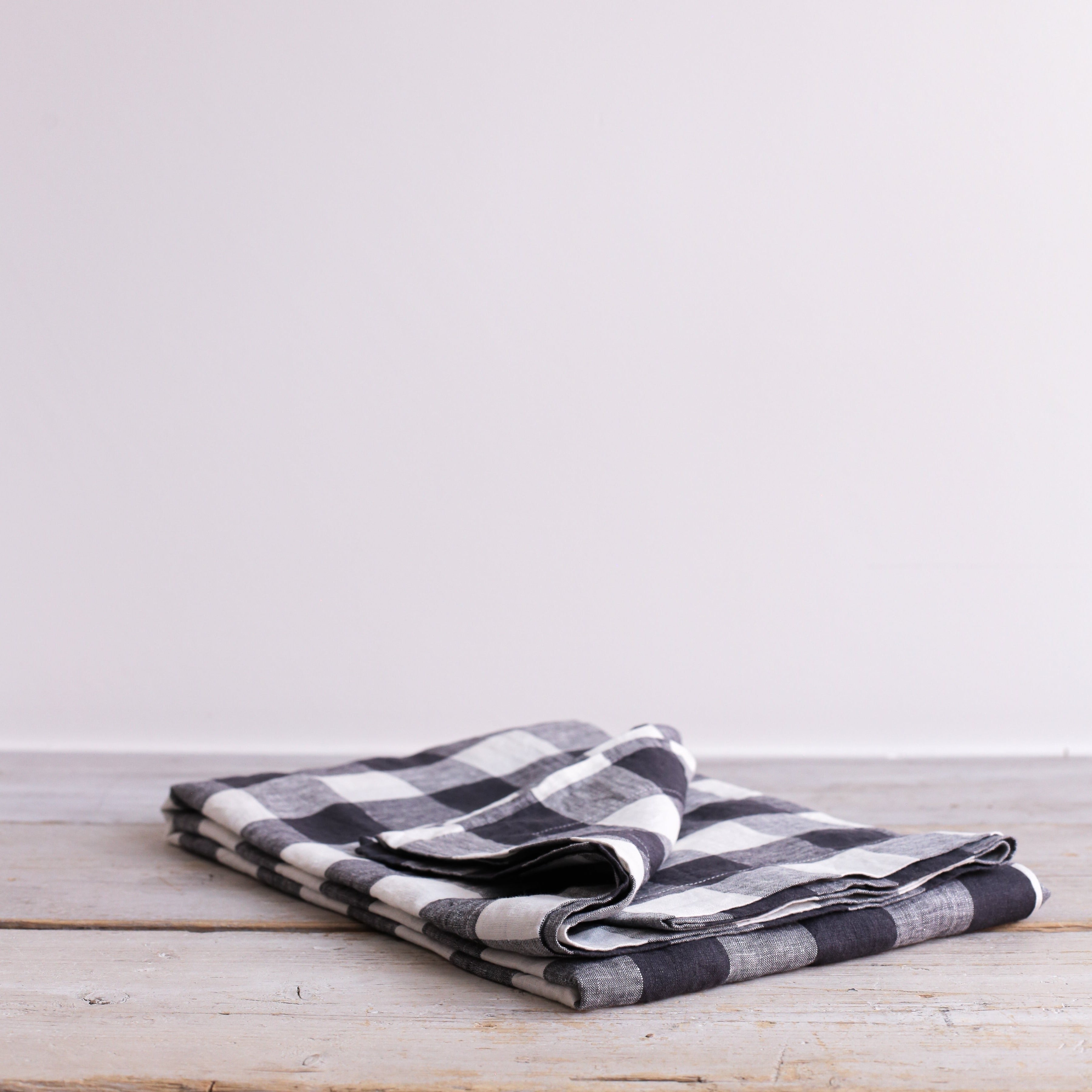 Black and white checkered linen tablecloth folded on a rustic wooden surface.