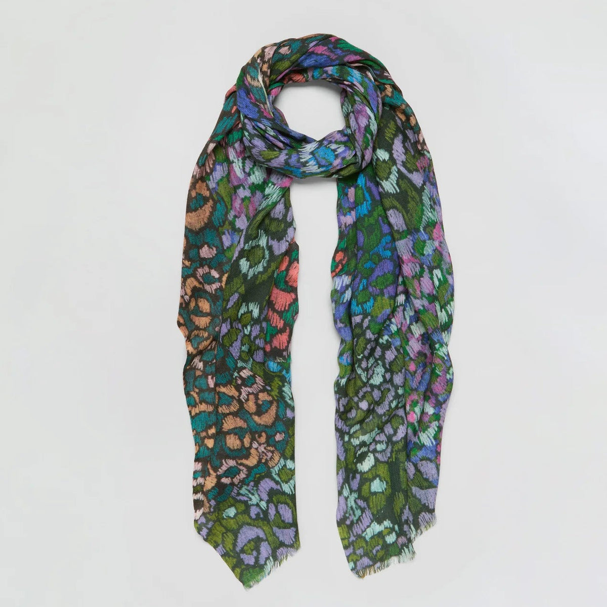 A lightweight scarf with a dense multicolor leopard print pattern featuring green, purple, orange, and blue tones, styled in a loop on a plain light gray background.