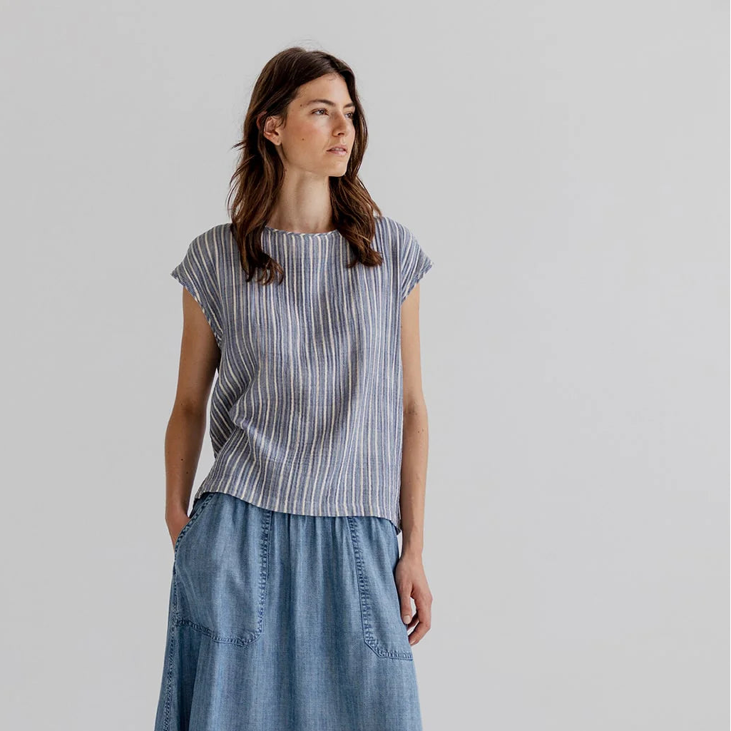 Woman wearing a striped shirt and denim skirt on a plain background