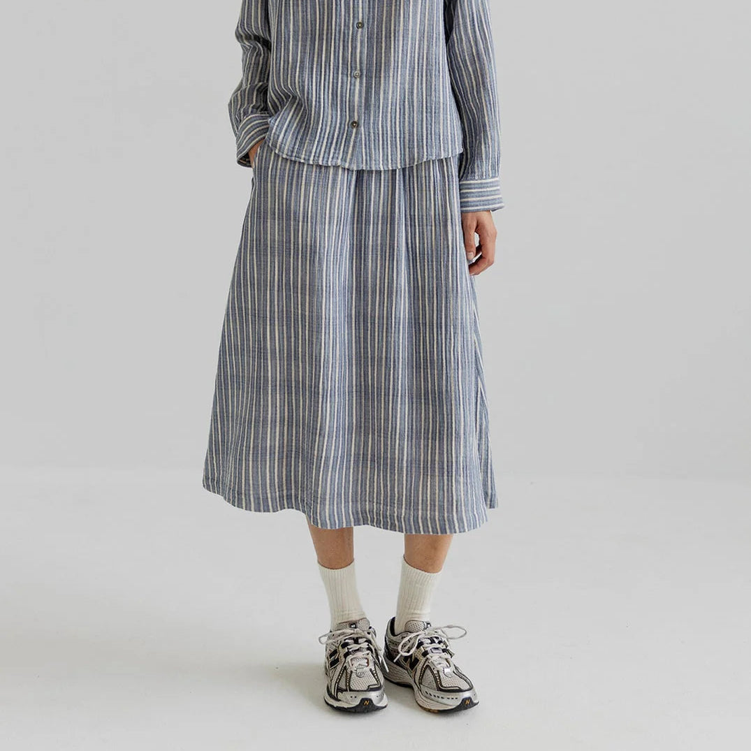 Woman wearing a striped shirt and skirt set on a plain background
