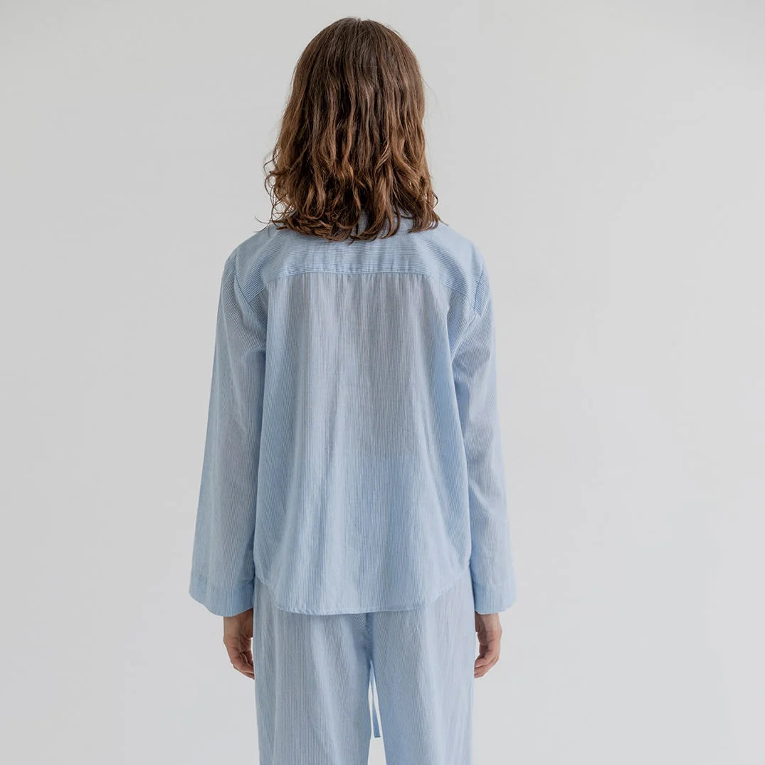 Person wearing a light blue pajama set with lace details on a white background