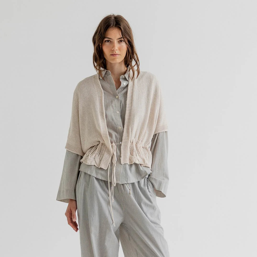 Woman wearing a light gray outfit with a scarf on a white background