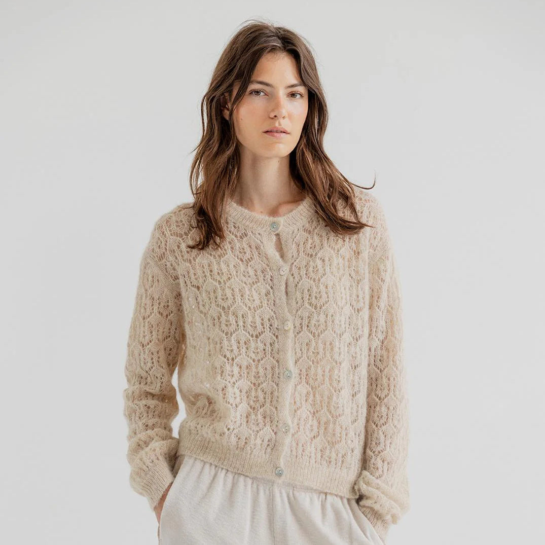 Woman wearing a beige knitted sweater against a plain background