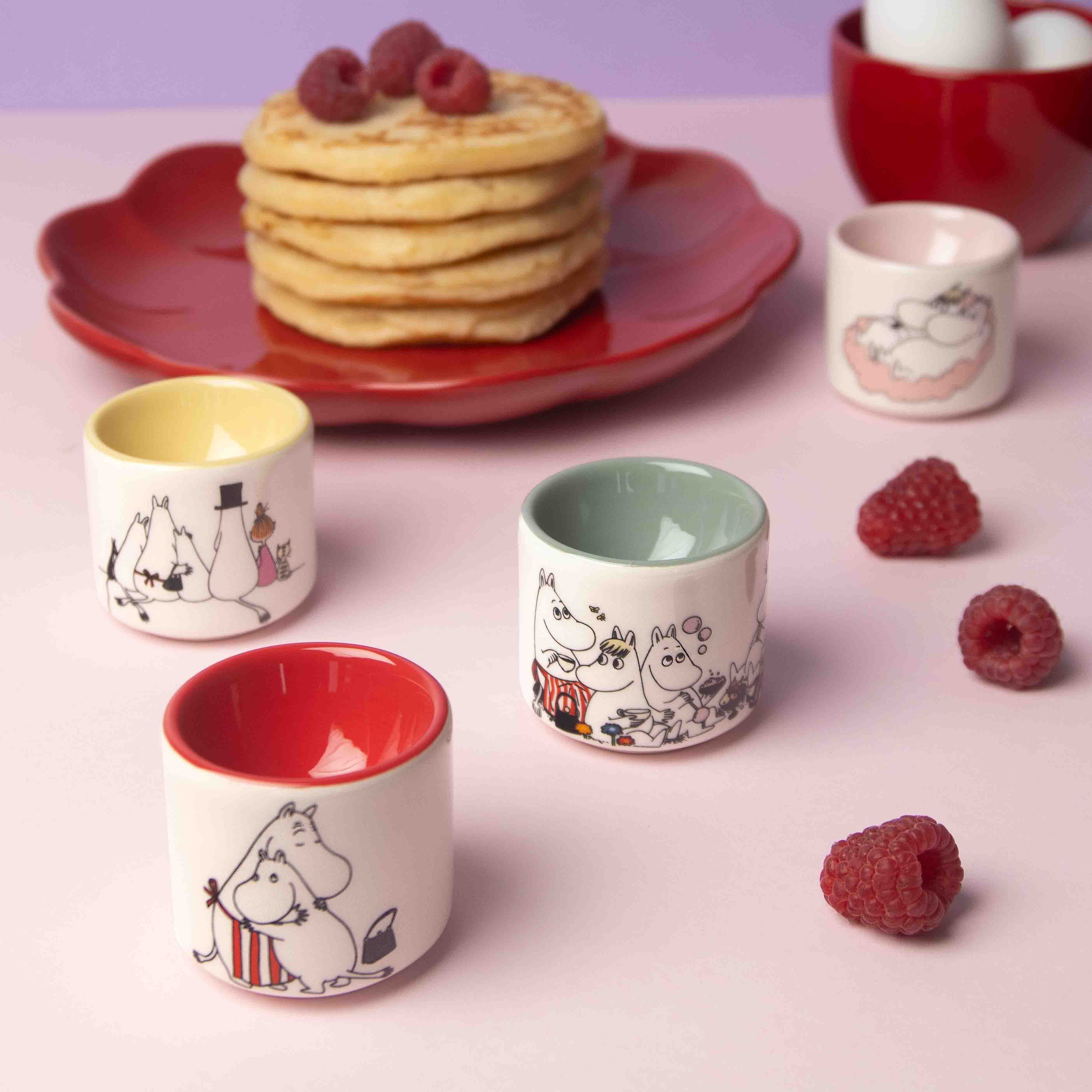 Set of four Moomin-themed ceramic egg cups in various colors; each cup features a different Moomin character illustration.