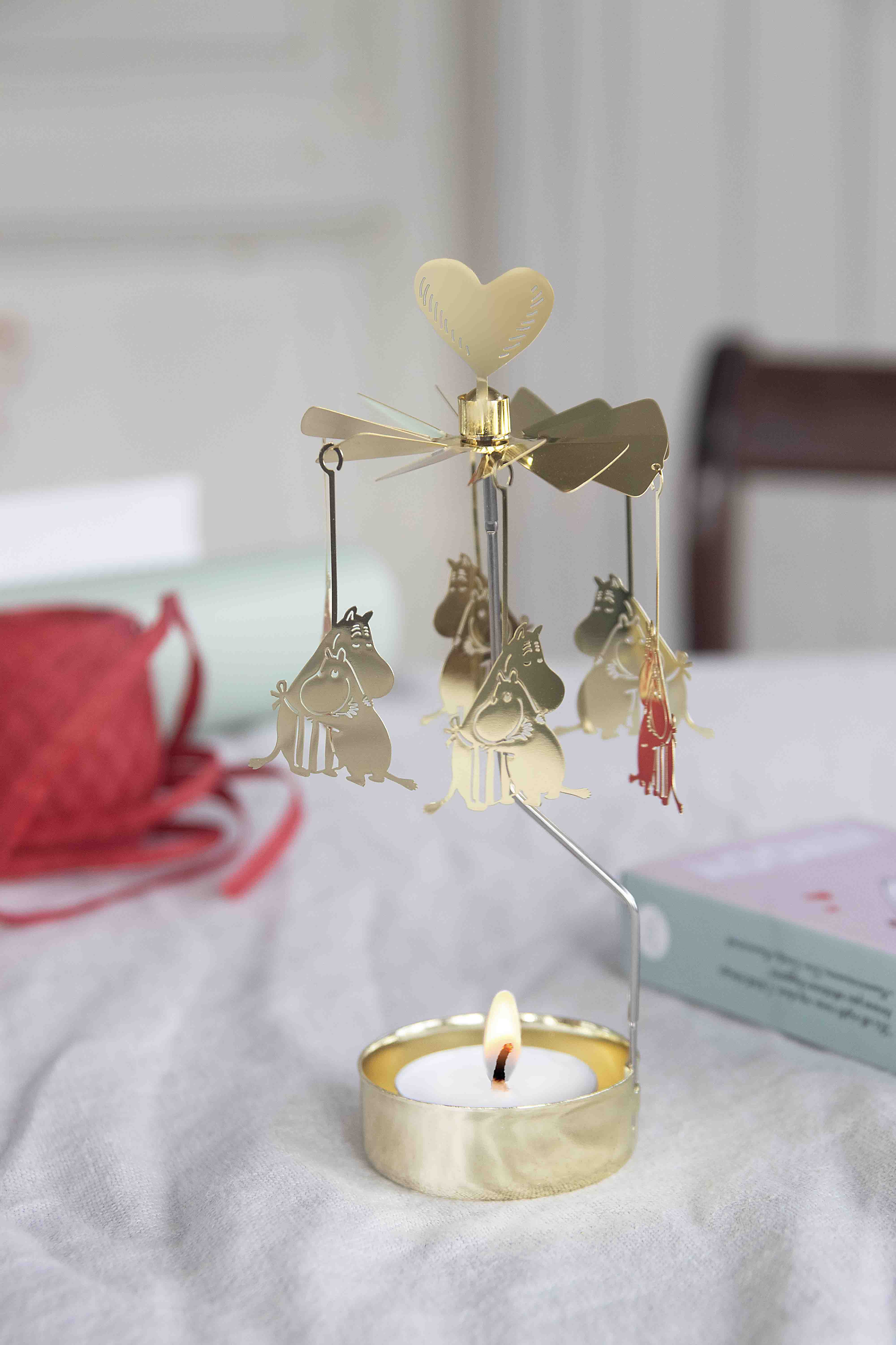 Gold carousel with heart top and small figures on a white surface with a blurred background