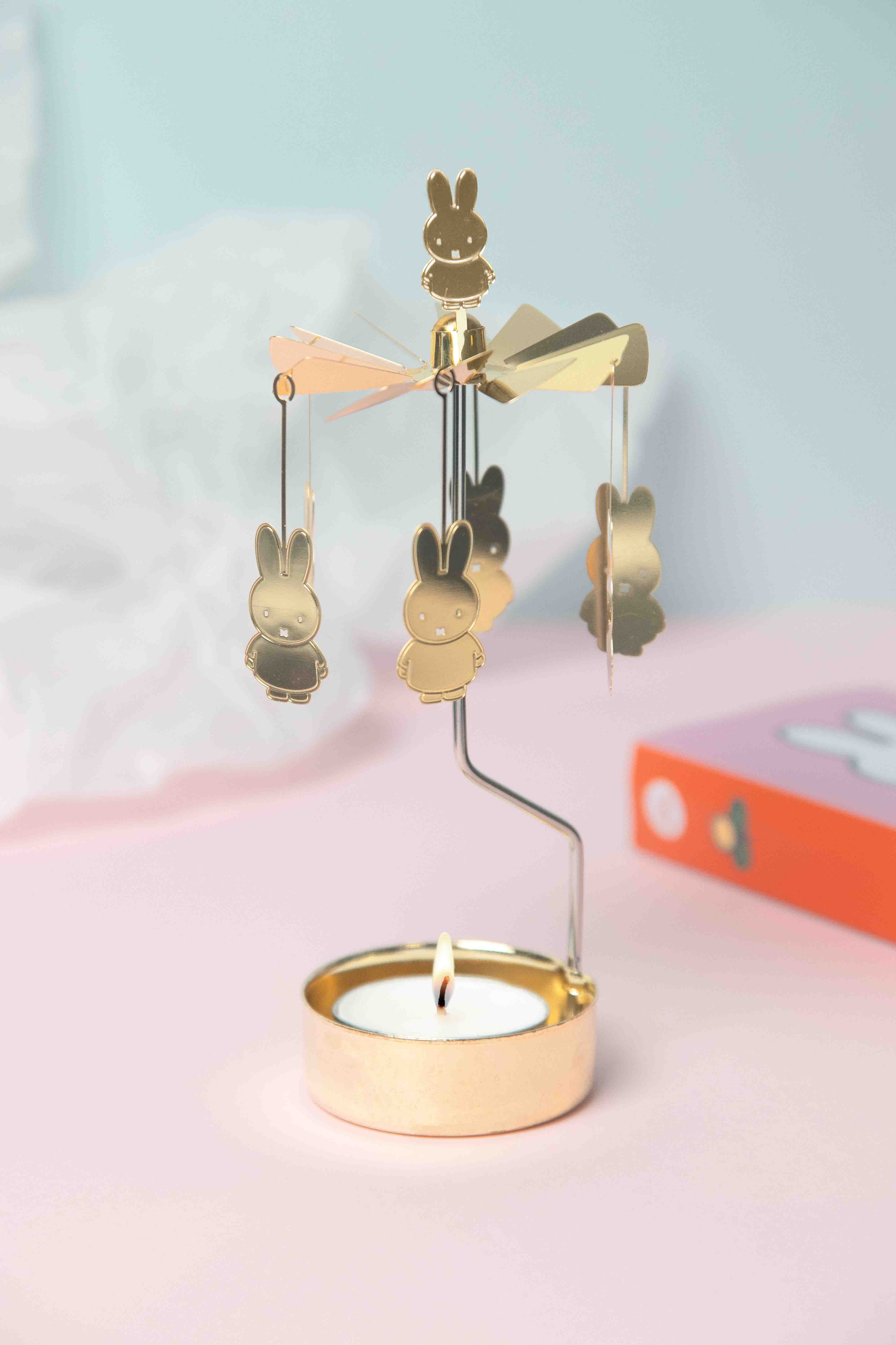 Gold Miffy candleholder with spinning Miffy figures and a lit tea light candle.