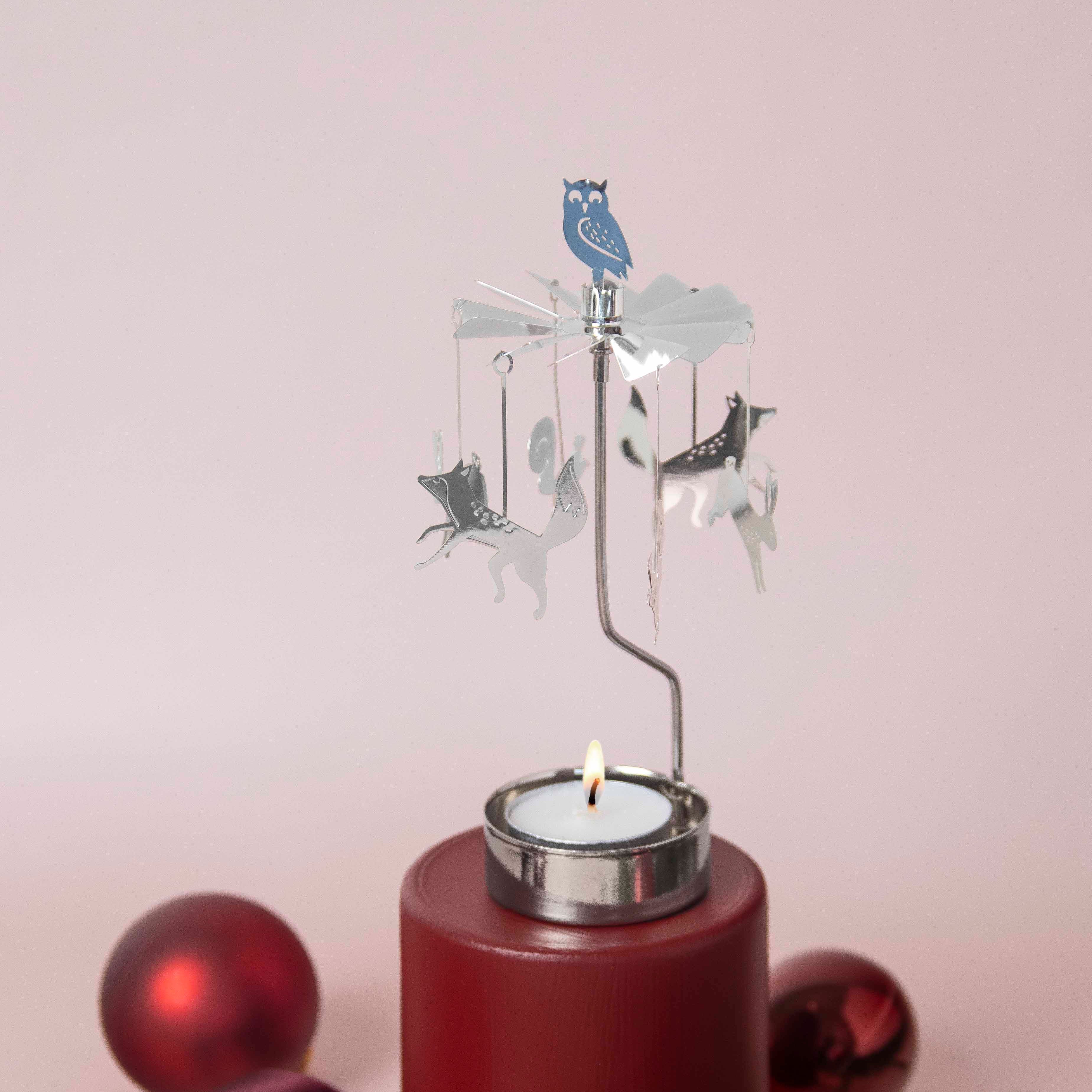 Decorative candle holder with a spinning animal design on a pink background