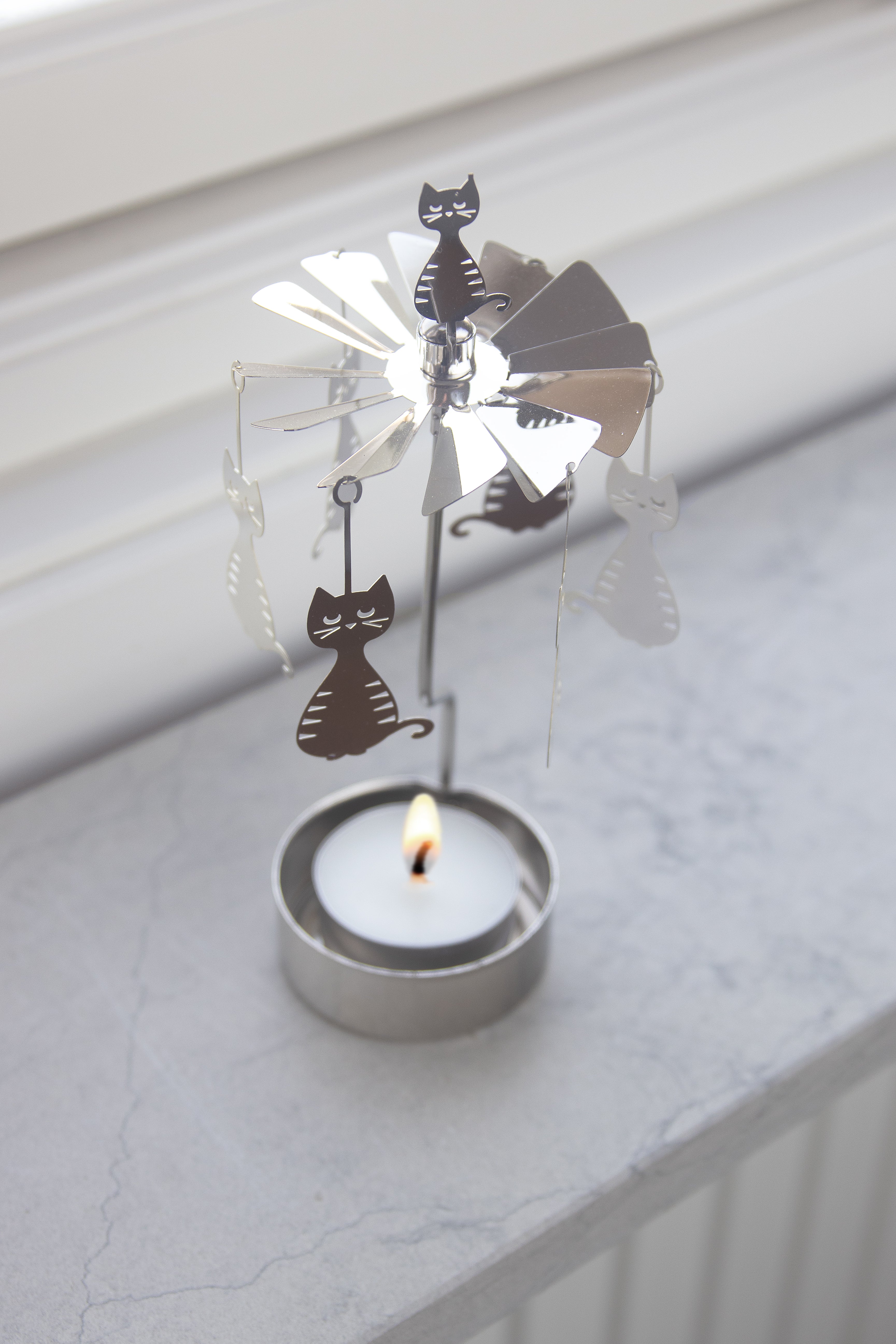 Decorative windmill with cats on a candle holder against a white background