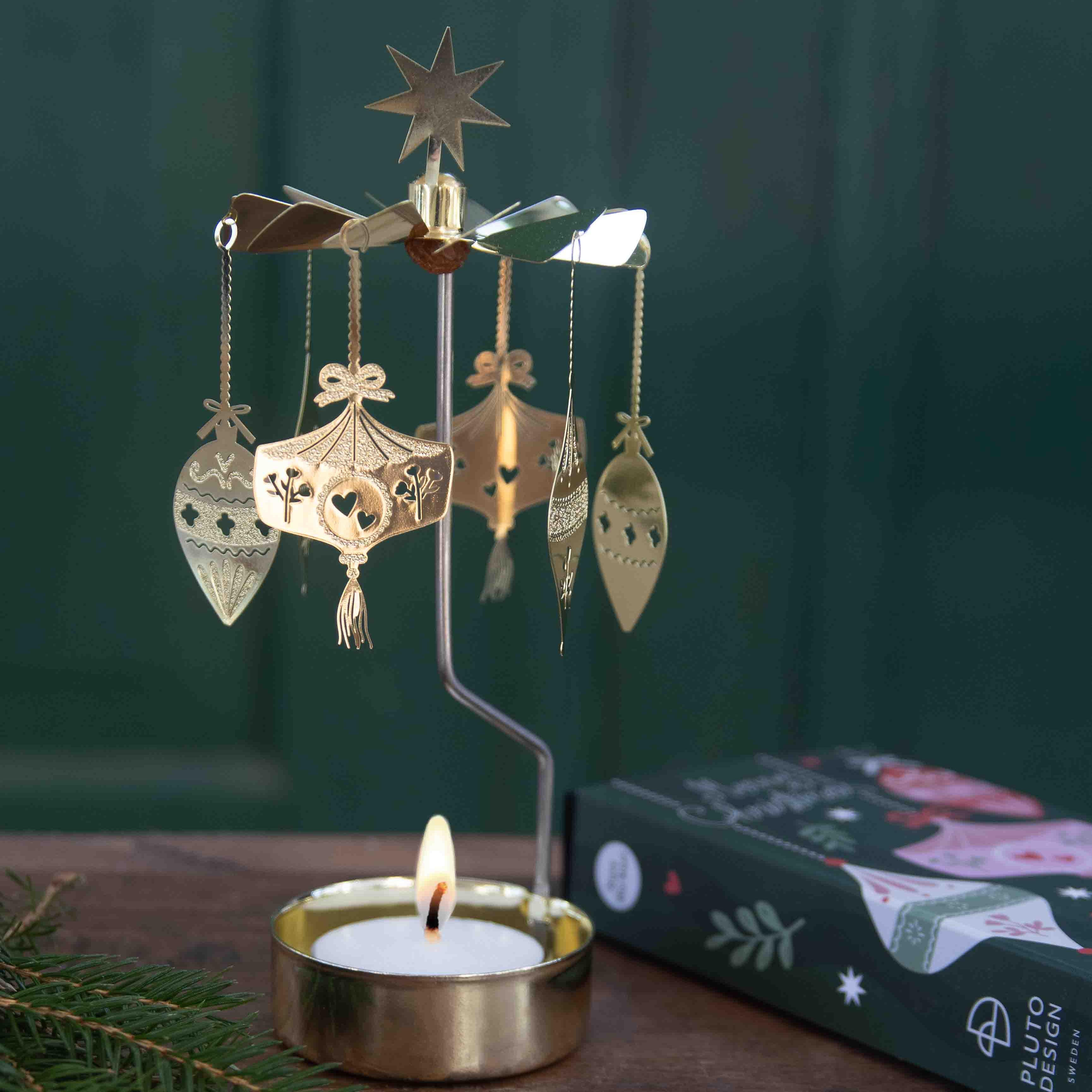 Decorative candle holder with hanging ornaments on a wooden surface with a green background