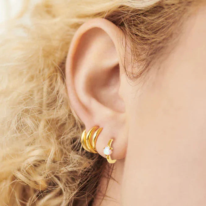 Close-up of an ear wearing gold hoop earrings with blonde hair.