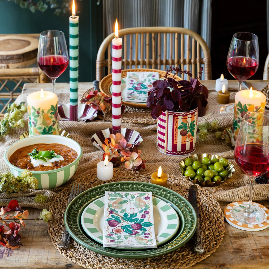 Decorative table setting with candles, wine glasses, and a bowl of soup.