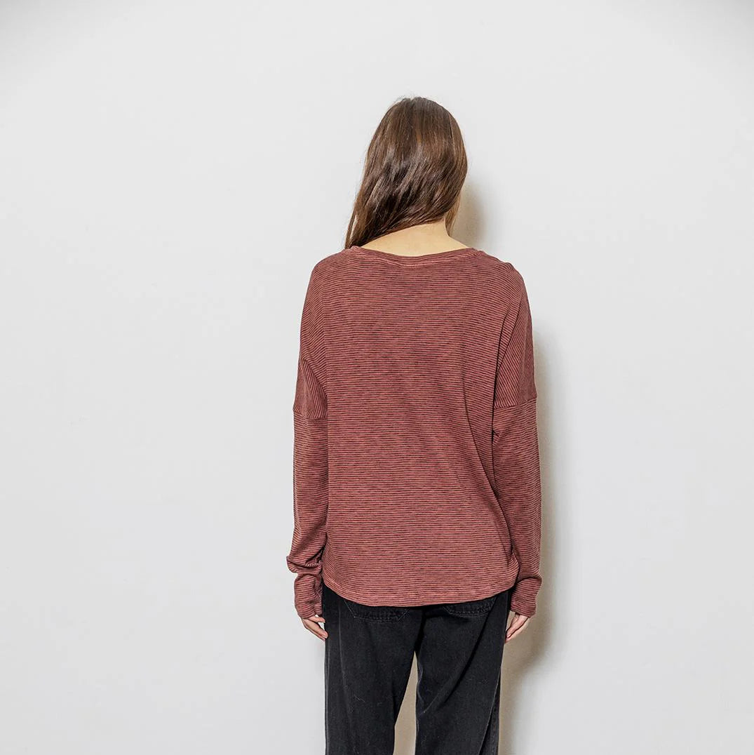 Person wearing a maroon long-sleeve shirt against a white background