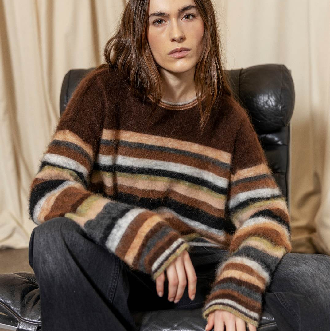 Person wearing a striped sweater sitting on a leather chair.