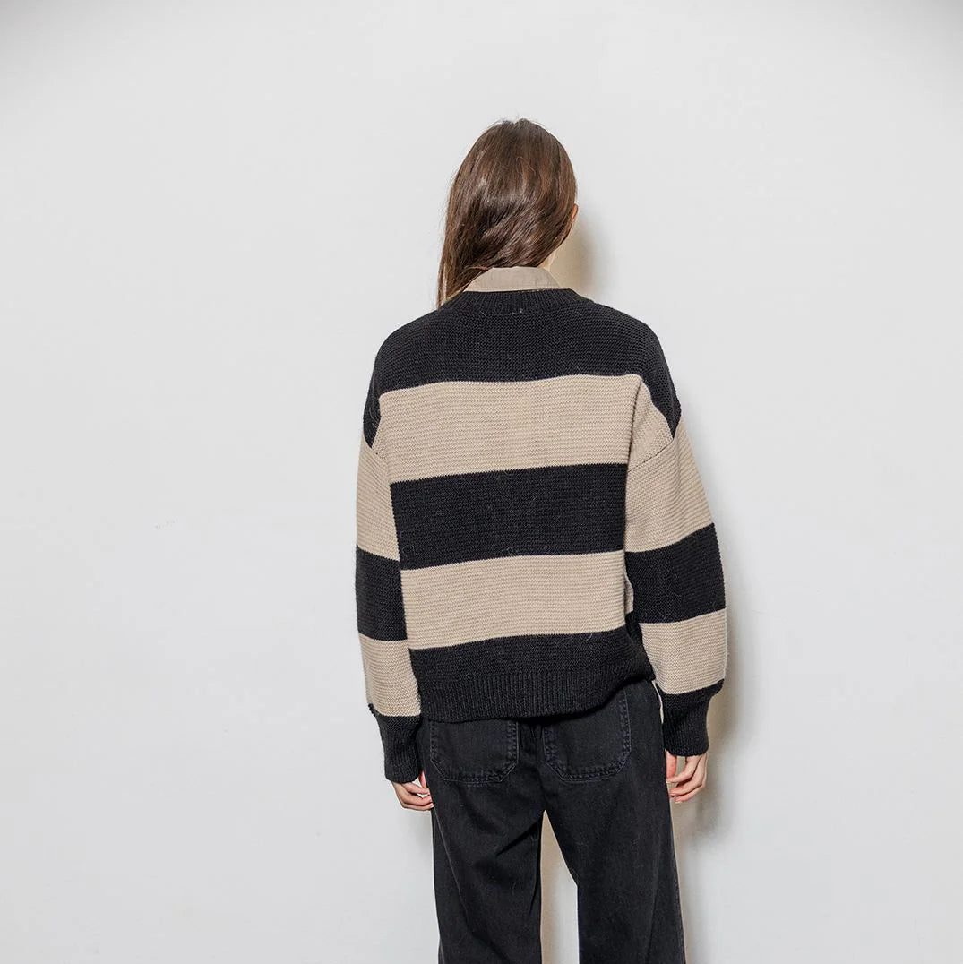 Person wearing a black and beige striped sweater against a white background
