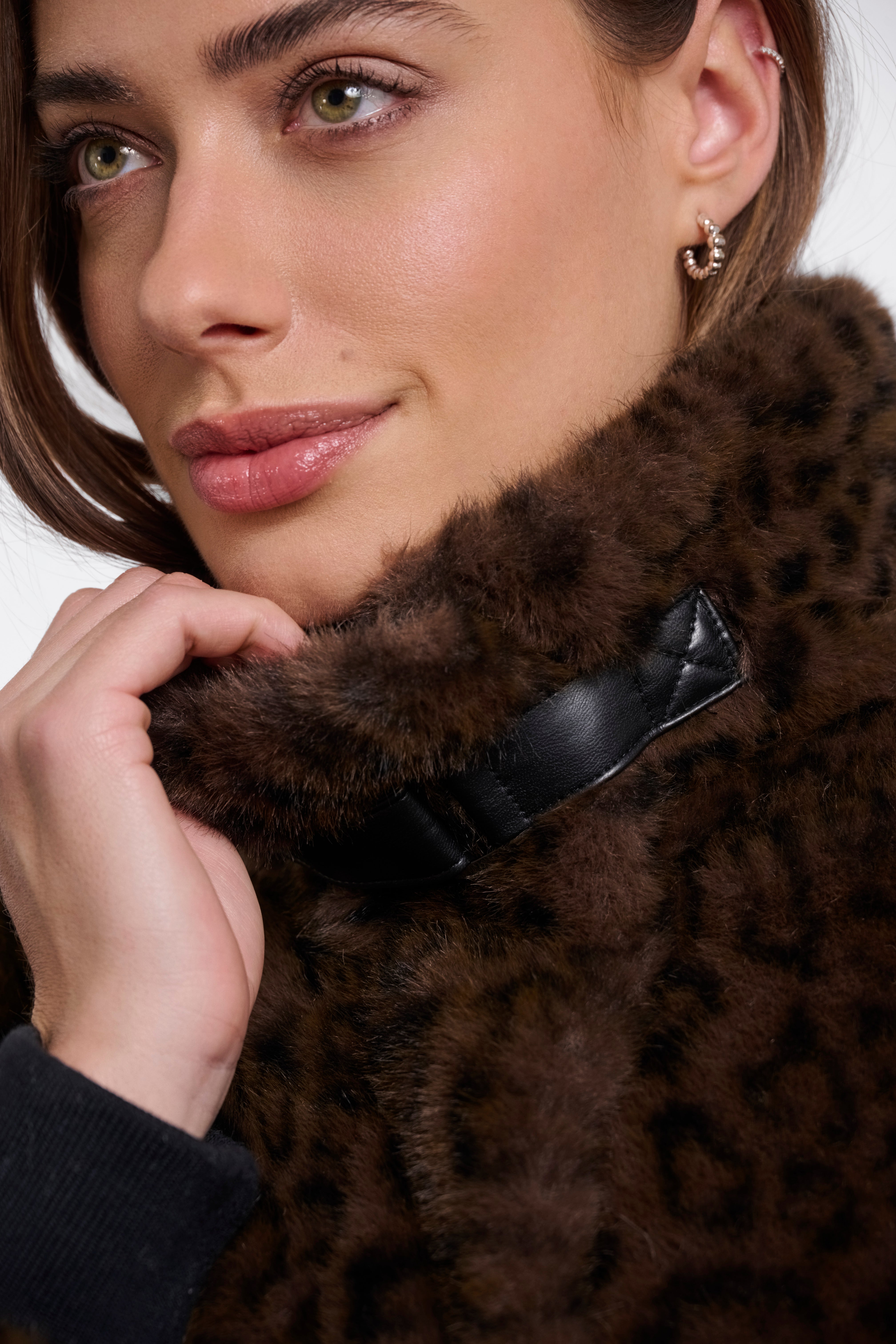 Close-up of a person wearing a brown fur coat with a white background