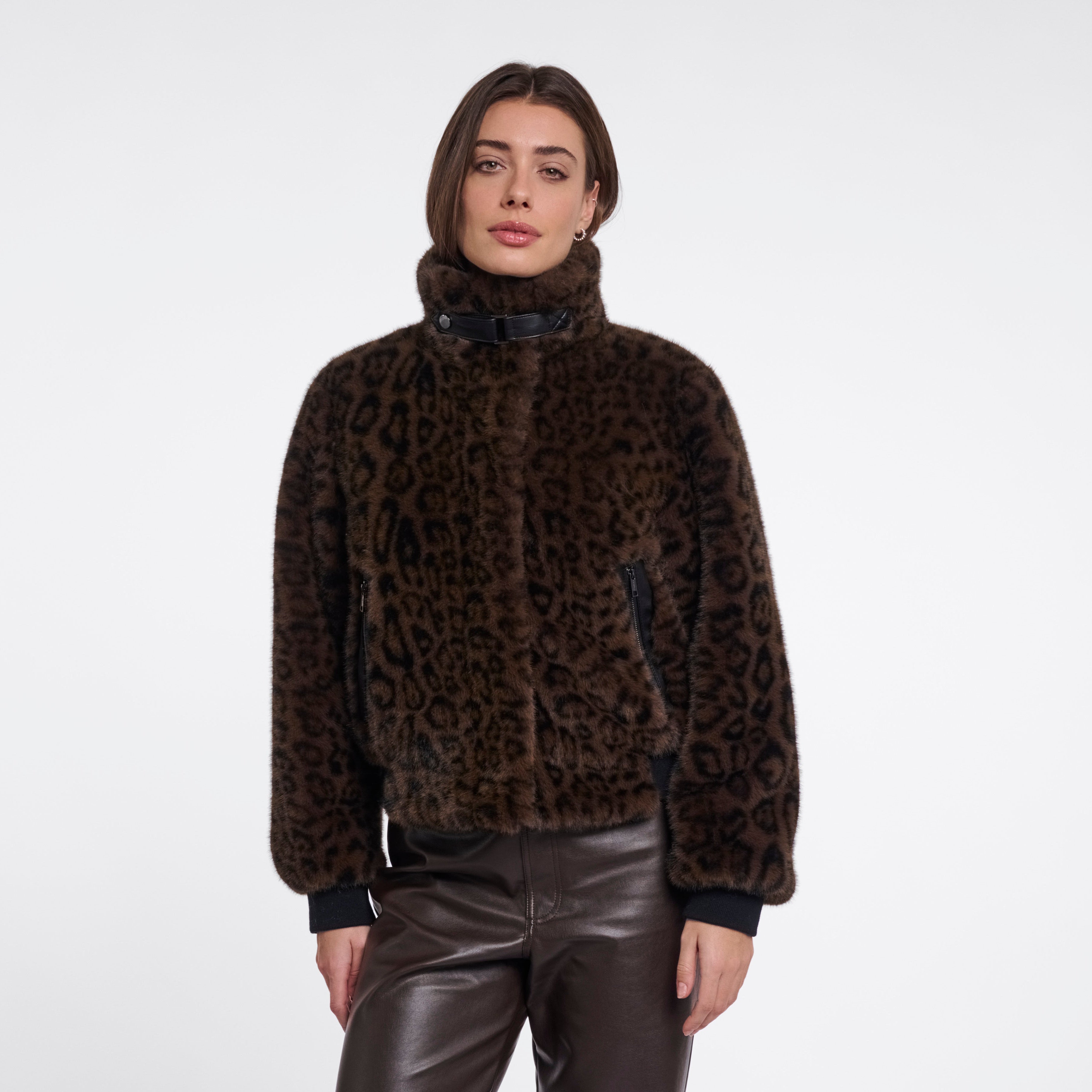 Person wearing a brown fur sweater and black leather pants on a white background