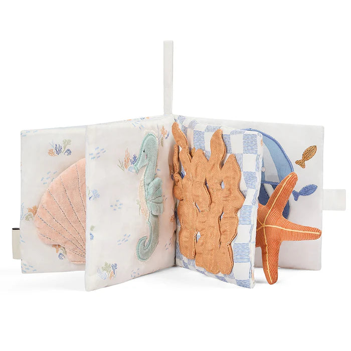 Children's soft book with ocean-themed illustrations and plush toys on a white background