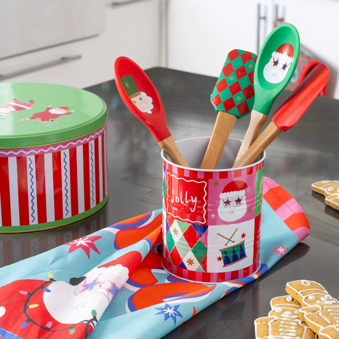 Set of Christmas-themed kitchen utensils in a decorative container on a kitchen counter.