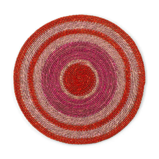 Round woven rug with concentric red and pink stripes on a white background