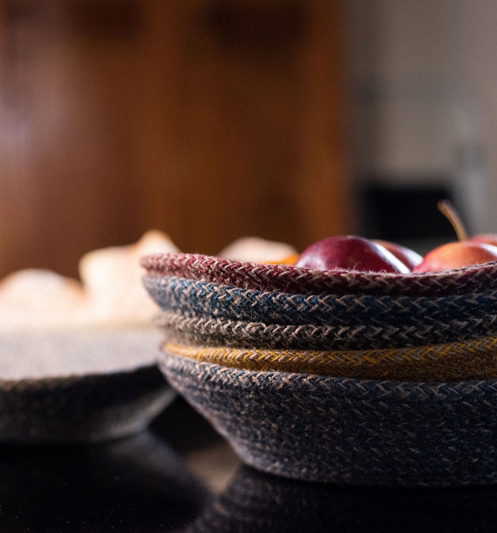 Stacked woven baskets containing red apples.  The baskets are multicolored with dark blue, maroon, and beige tones.