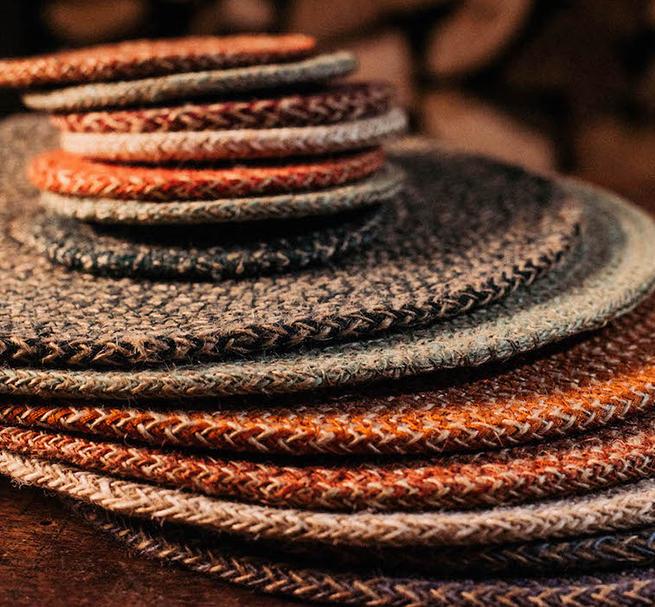 Stack of jute coasters in various earthy tones;  textured woven fabric with visible herringbone pattern.