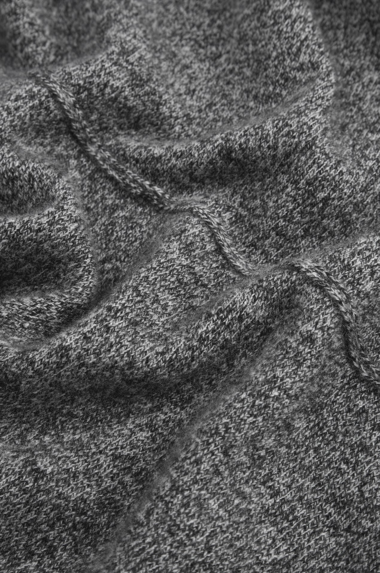 Close-up of a dark heather gray knit fabric with a ribbed or textured weave and stitched seam details.