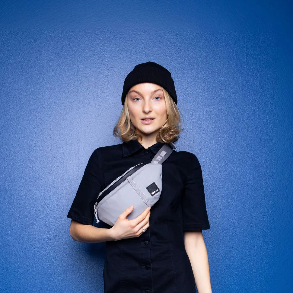 Light gray crossbody bag with black accents, worn by a model.