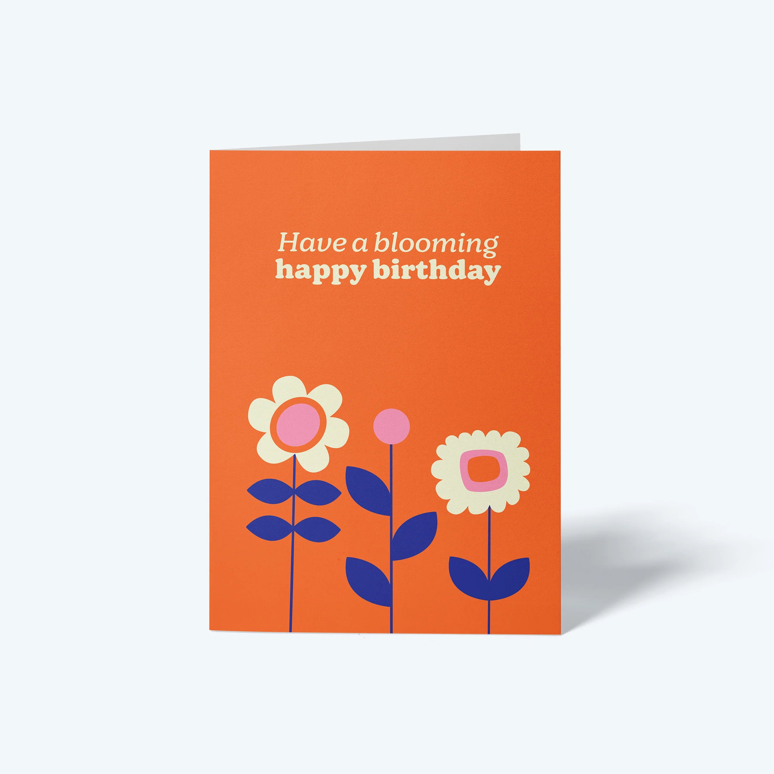 Orange birthday card with floral designs and text 'Have a blooming happy birthday' on a white background.