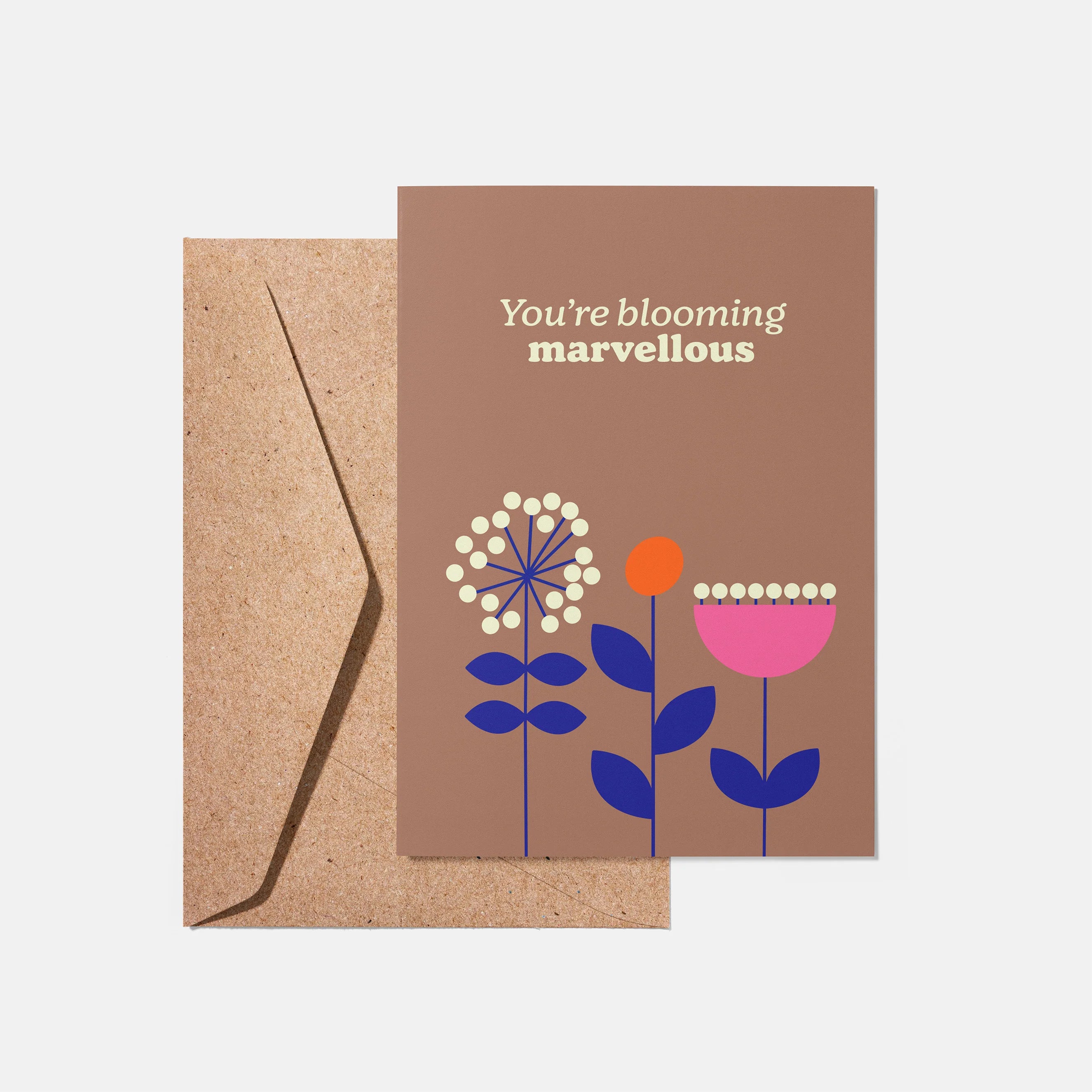 Greeting card with floral design and 'You're blooming marvellous' text on a brown background, accompanied by a kraft envelope.